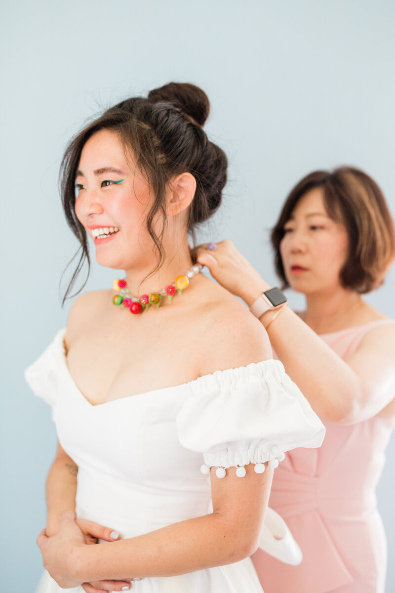 The bride's mother puts a necklace on her daughter as she gets ready for her wedding at Dos Pueblos Orchid Farm in Santa Barbara.