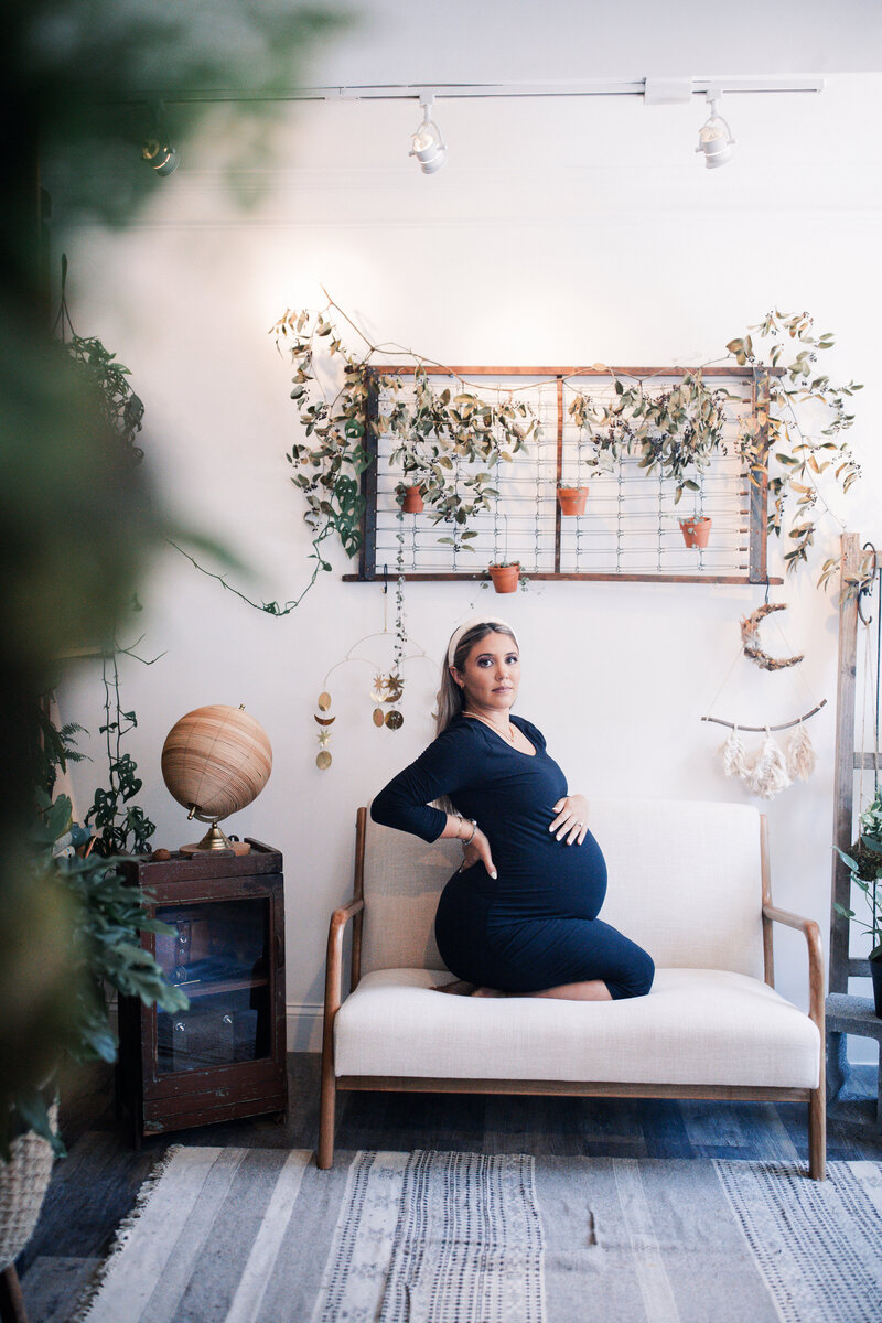 An expectant mom sits in a greenhouse for a maternity session