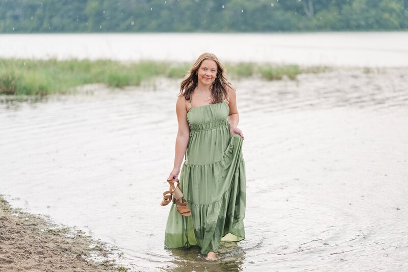 a girl in a green dress standing in shallow water