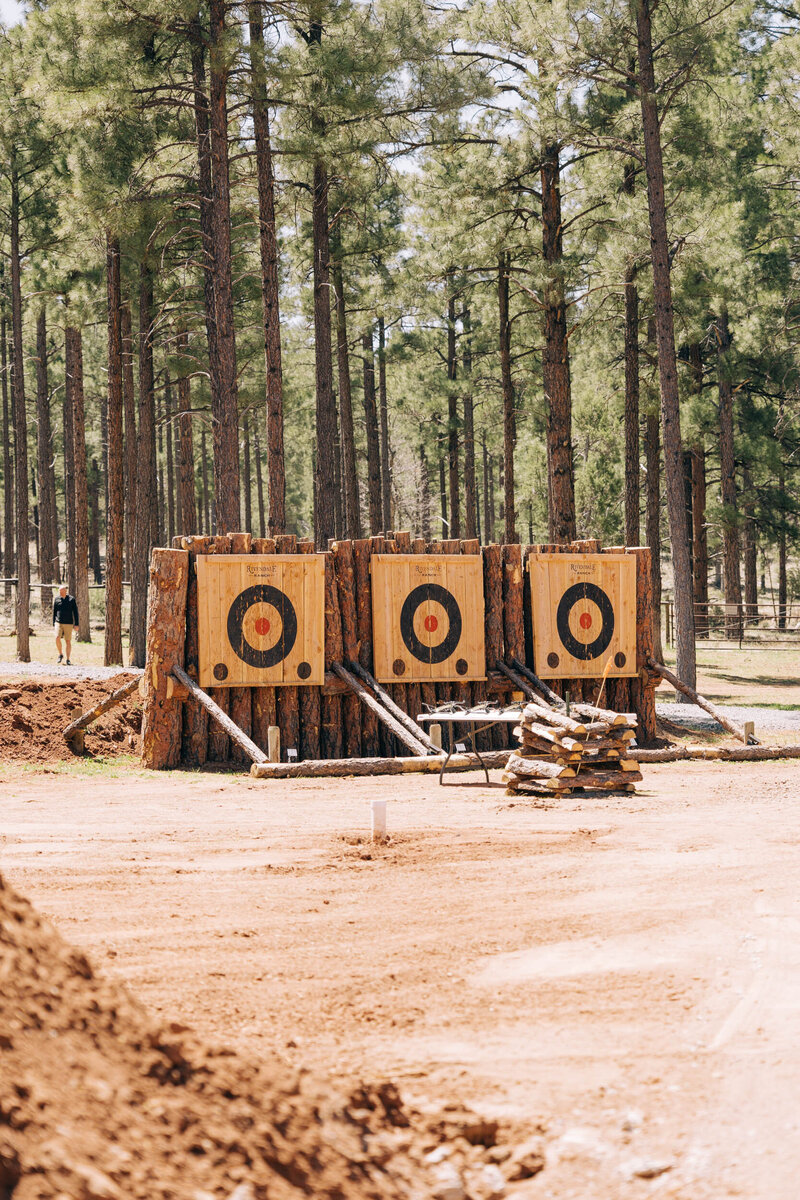 Three large wooden axe throwing targets sit in a clearing in the middle of a ponderosa pine forest. 