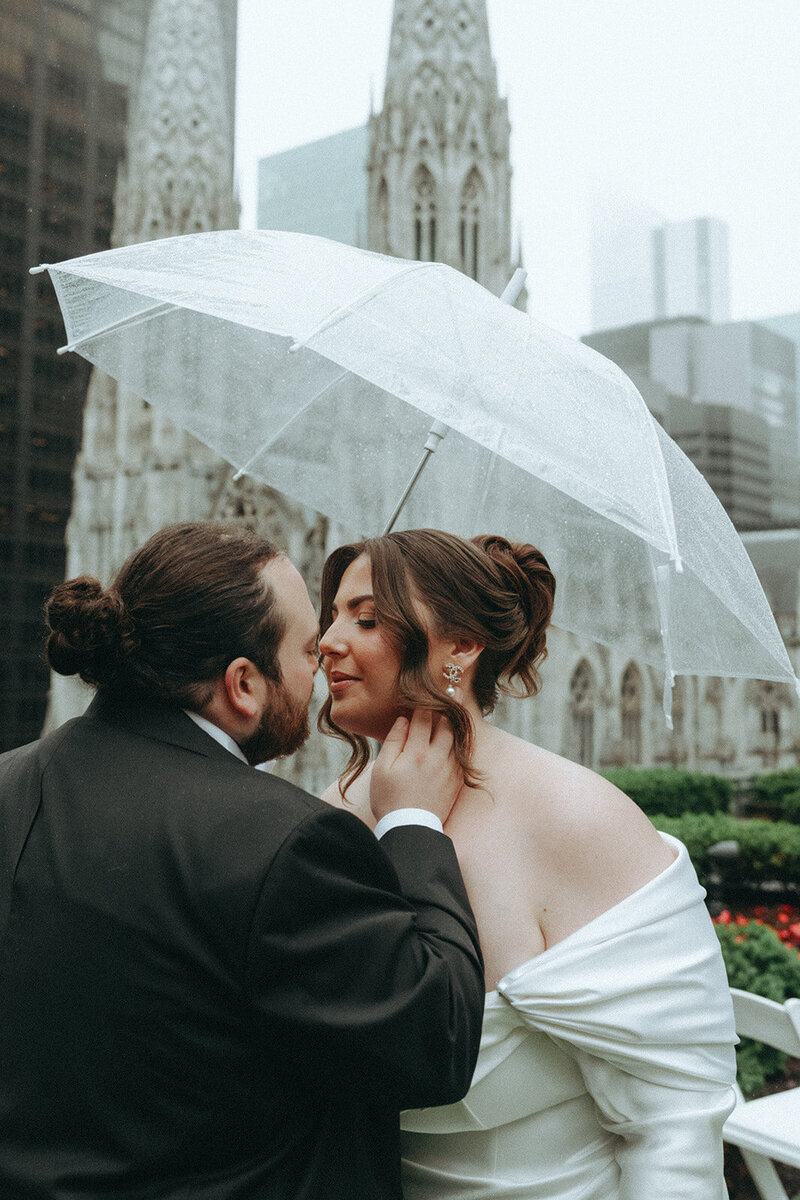 bride and groom kissing at 620 loft & garden under an umbrella before elopement ceremony shot by Elsie Goodman Photography | NYC Elopement Packages