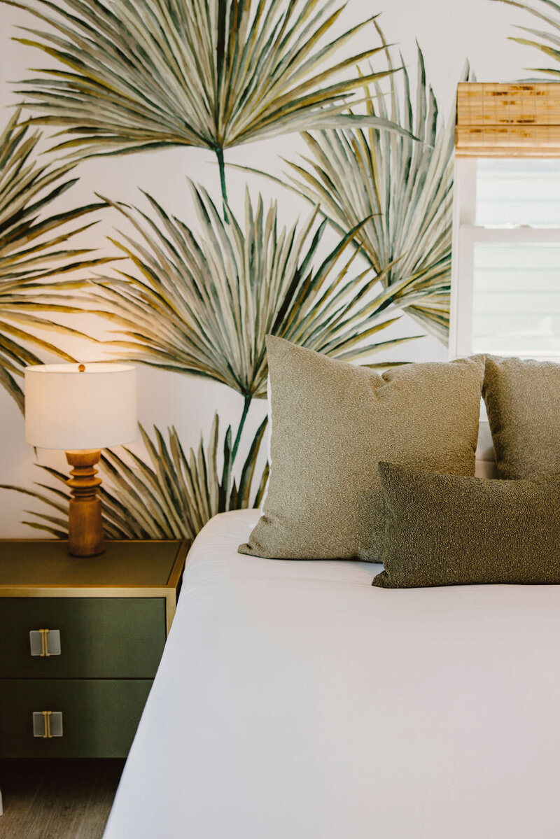 Bed with white linens, green pillows, and green night stand