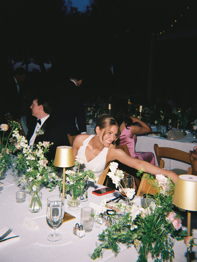 Flash film photo of bride and groom at reception table decorated with greenery
