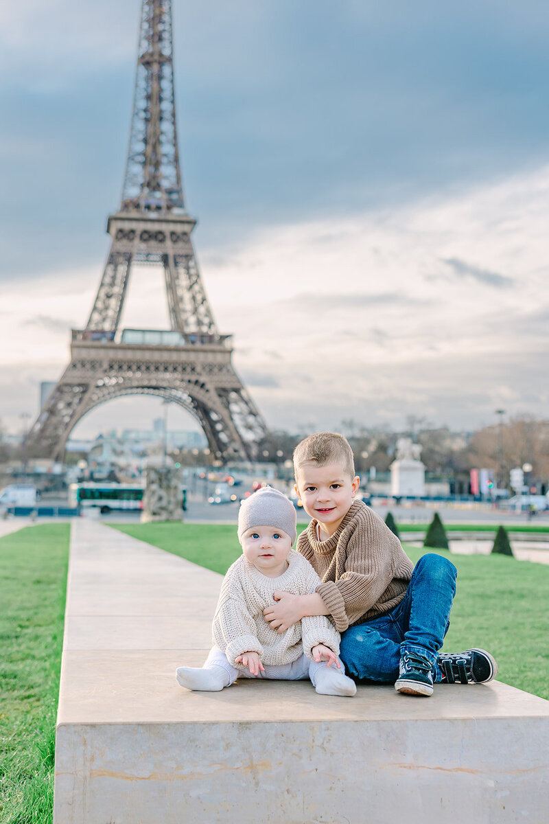 Young boy and baby in front of the Eiffel Tower at Trocadéro during a Paris family photoshoot.