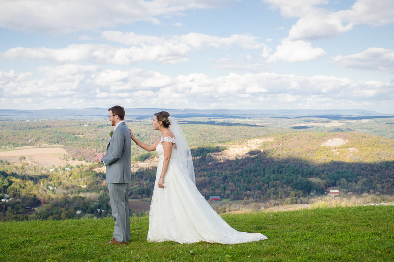 Bride tapping the groom on the shoulder during their first look at Blue Mountain, with views of Lehigh Valley and the Poconos in the background.