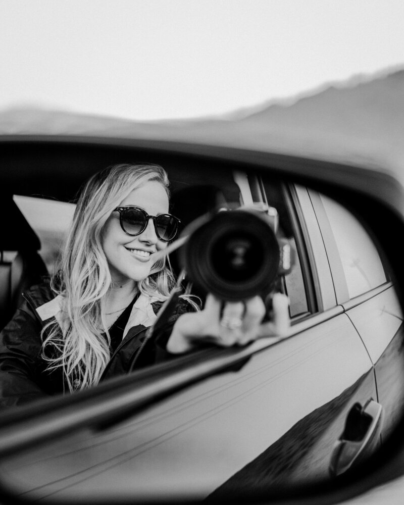 woman posing with camera in car