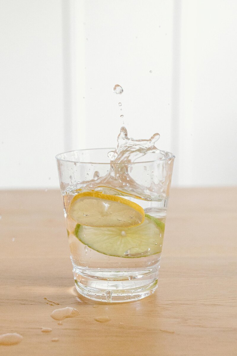 Lemon and lime slices splashing into a glass of water