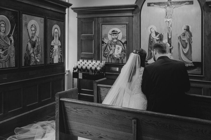 a bride and groom sitting on a church pew
