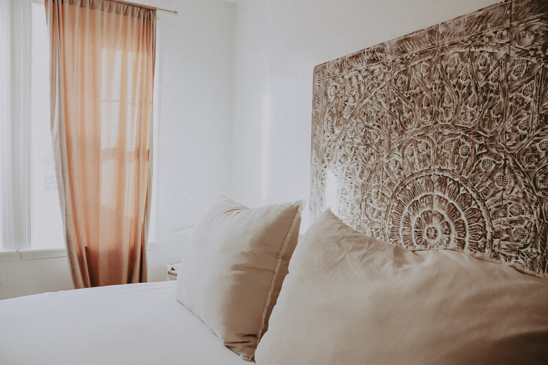 bed with white sheets and a wooden decorative headboard