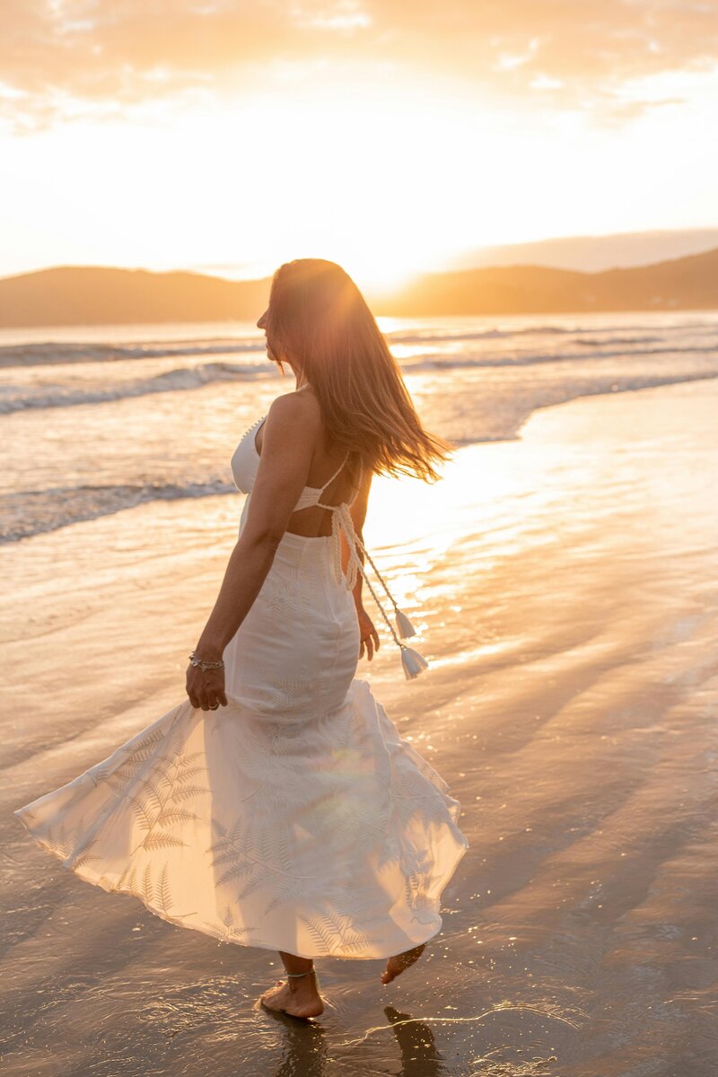 woman in a white dress on a beach at sunrise