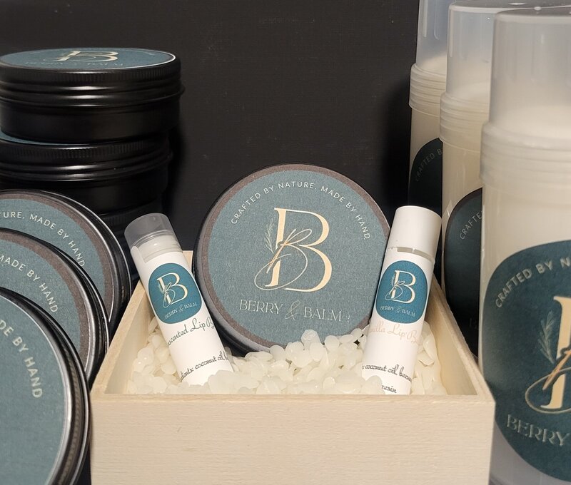 Berry and Balm body balm and lip balm products in a wooden box with the branding logos