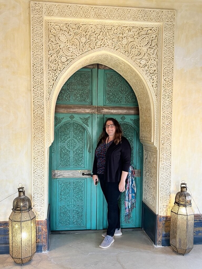 Elyn stands smiling in front of an ornate door in Morocco