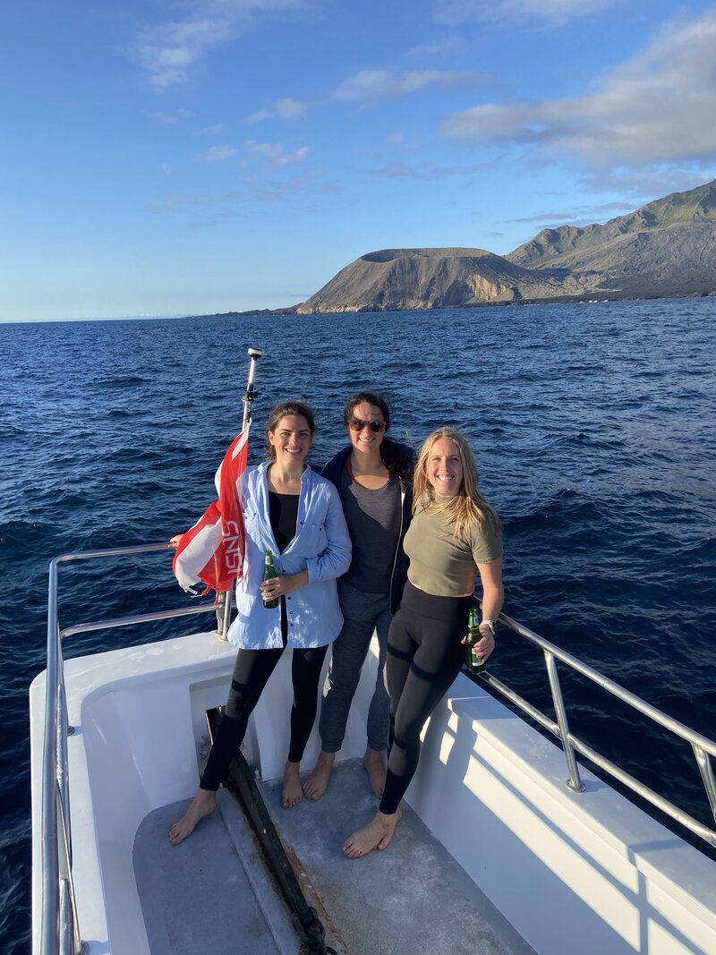 Three female divers hold Ecuadorian flag on a liveaboard trip in the Galapagos