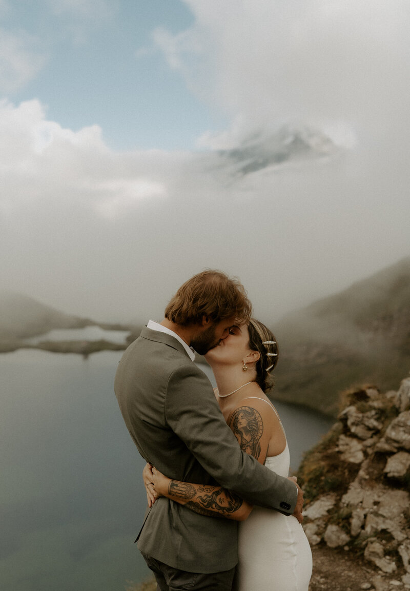 Bride and groom sharing their first kiss atop a breathtaking mountain in Switzerland, surrounded by stunning alpine views.