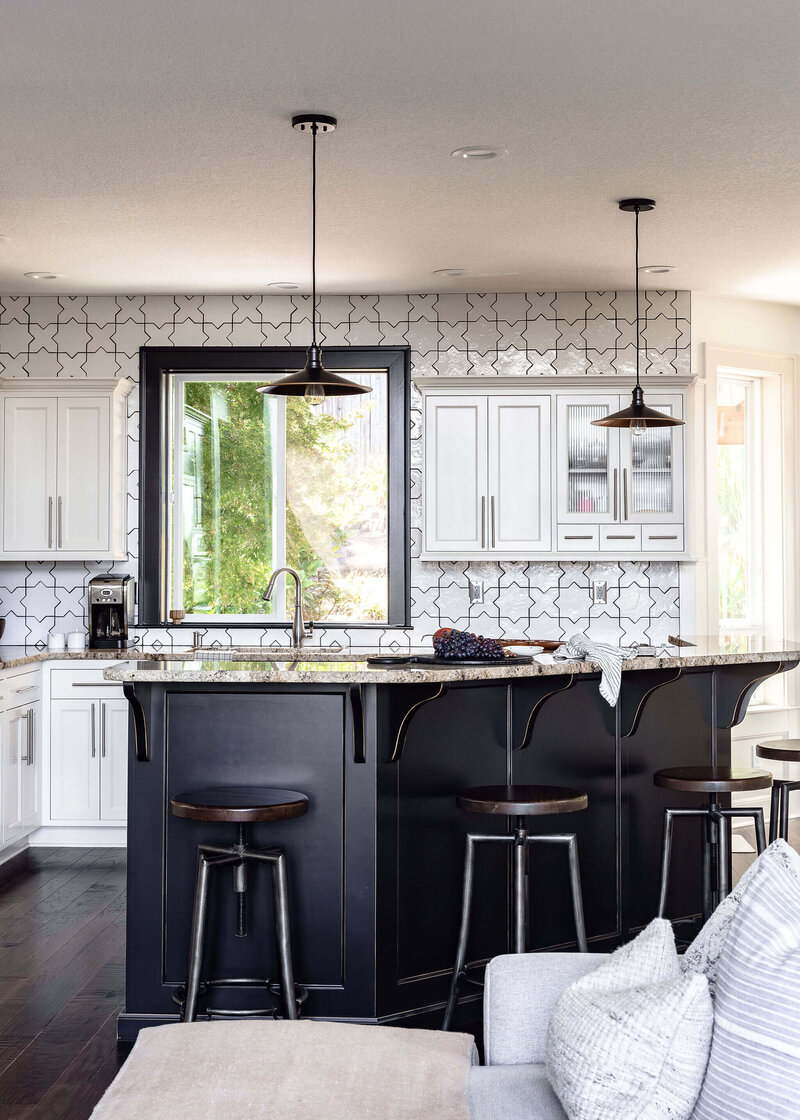 A kitchen with a large island and hanging light fixtures, representing a custom home interior designed by Winsome Home Interiors.