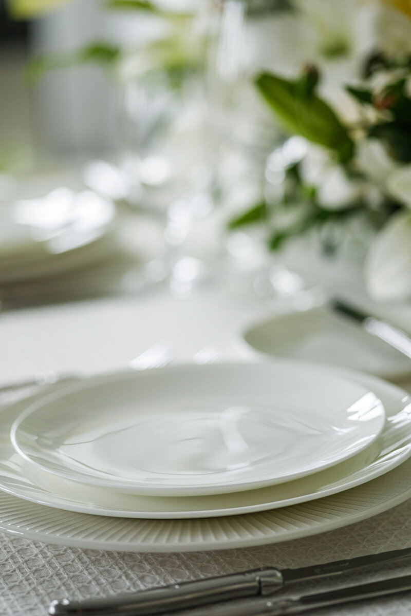 Close up of stack of white dishes on a wedding reception table