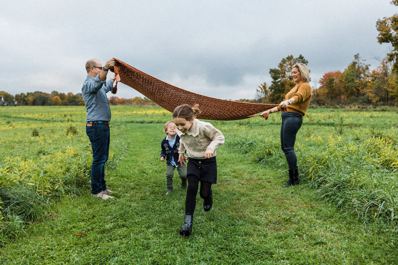 Mom and dad playing parachute with two children in a field