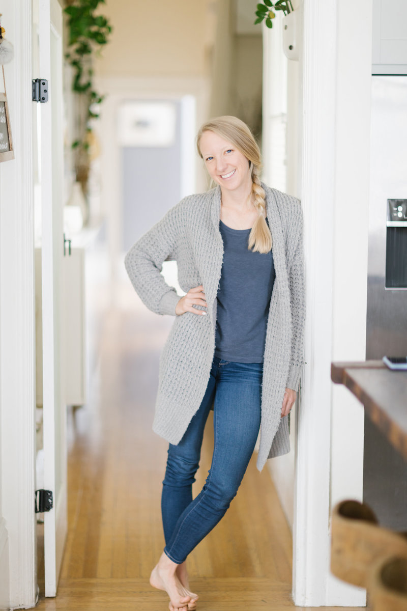 Kristin Hedstrom, an Olympian and erg coach, leaning against a door frame smiling at the camera.