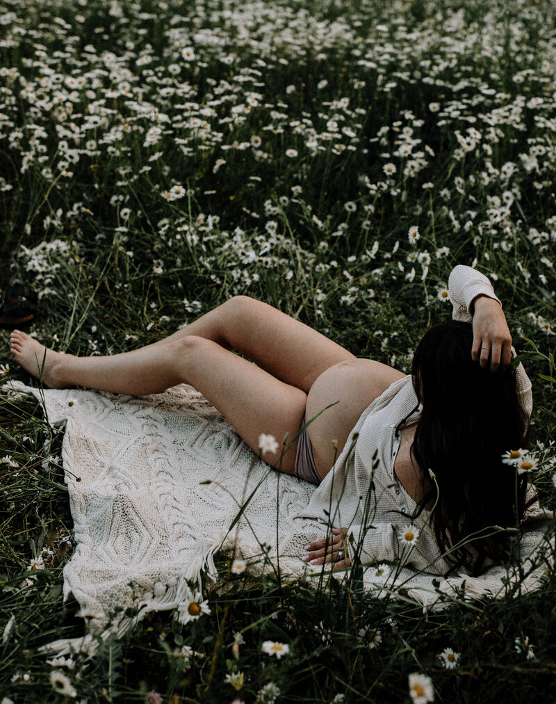 Pregnant Person Lying in Daisy Field