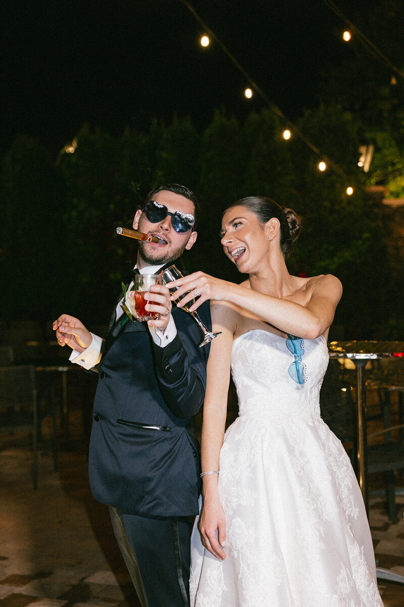 Bride and groom toast cups and laugh while under the lights of the Somerly at Fox Hollow on Long Island. 