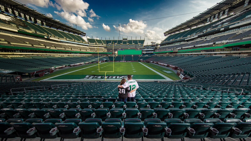 Couple in Eagles jerseys gazing at the entire empty Lincoln Financial Field, capturing a unique sports-themed engagement session.