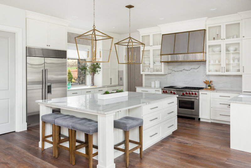 Modern Traditional white kitchen with stainless steel range hood and oversized island