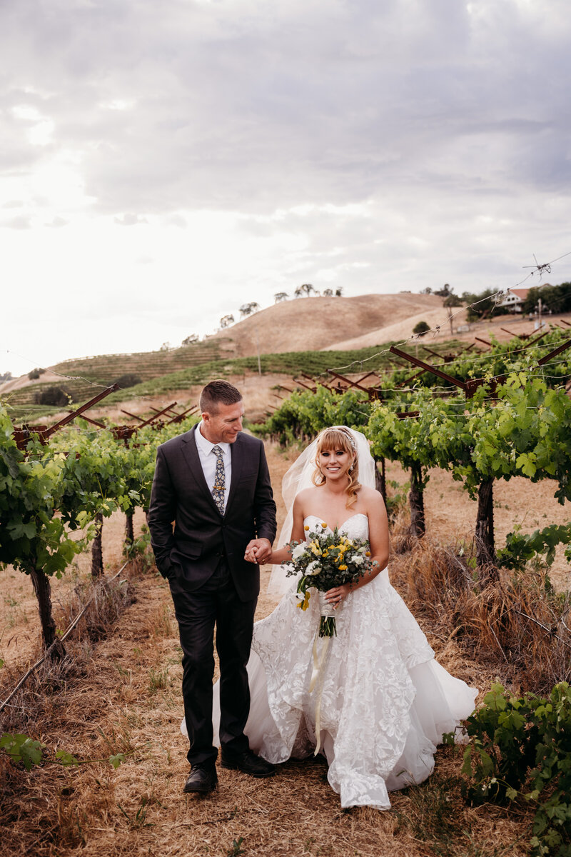 Bride and groom walking through the vineyard during their California elopement