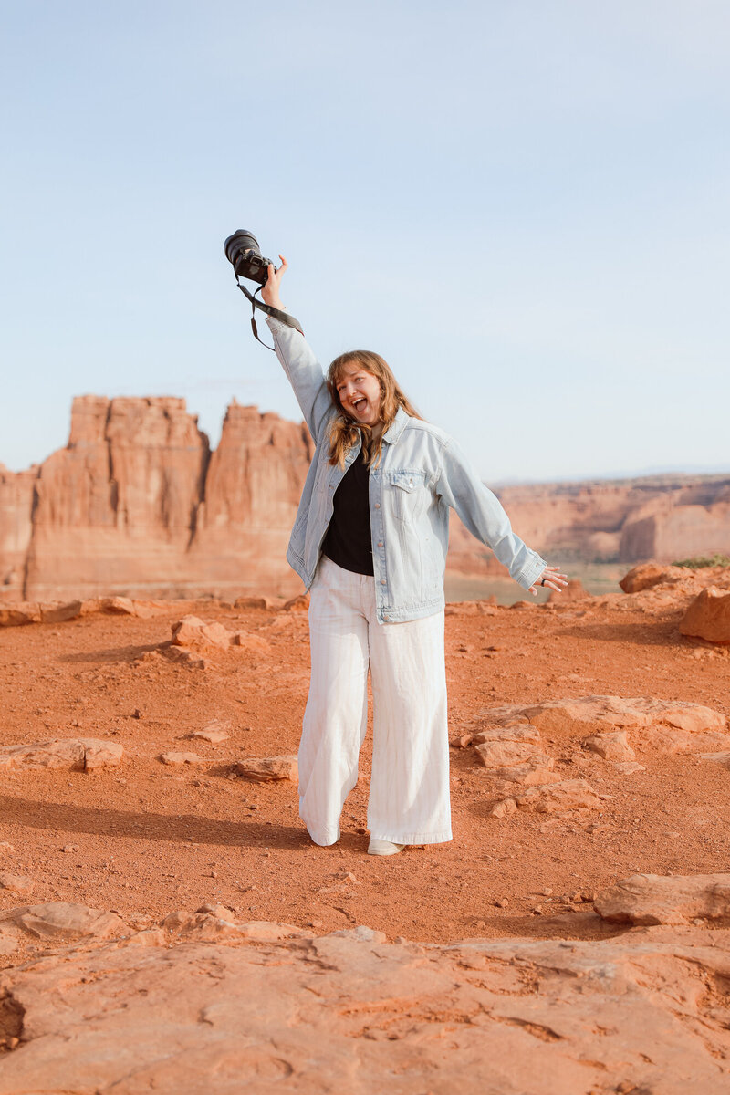 Candid photographer smiling with arm in the air at Arches National Park 