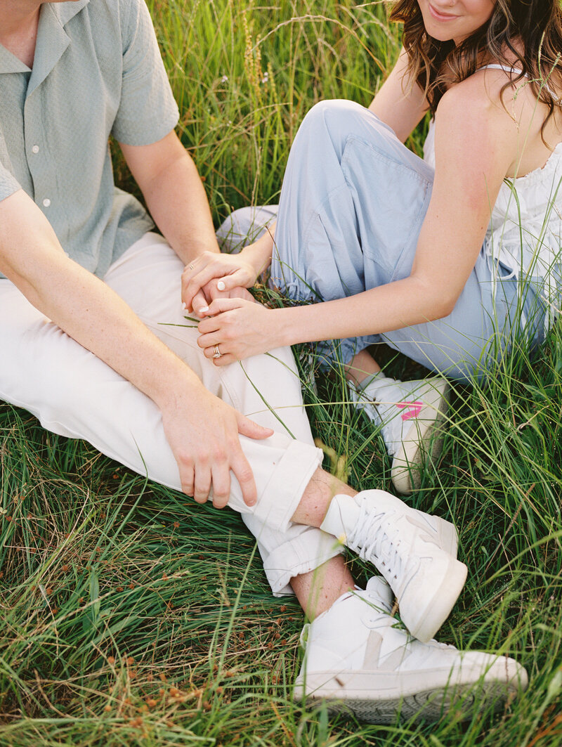 Close up of couple's crossed legs sitting in a grassy field