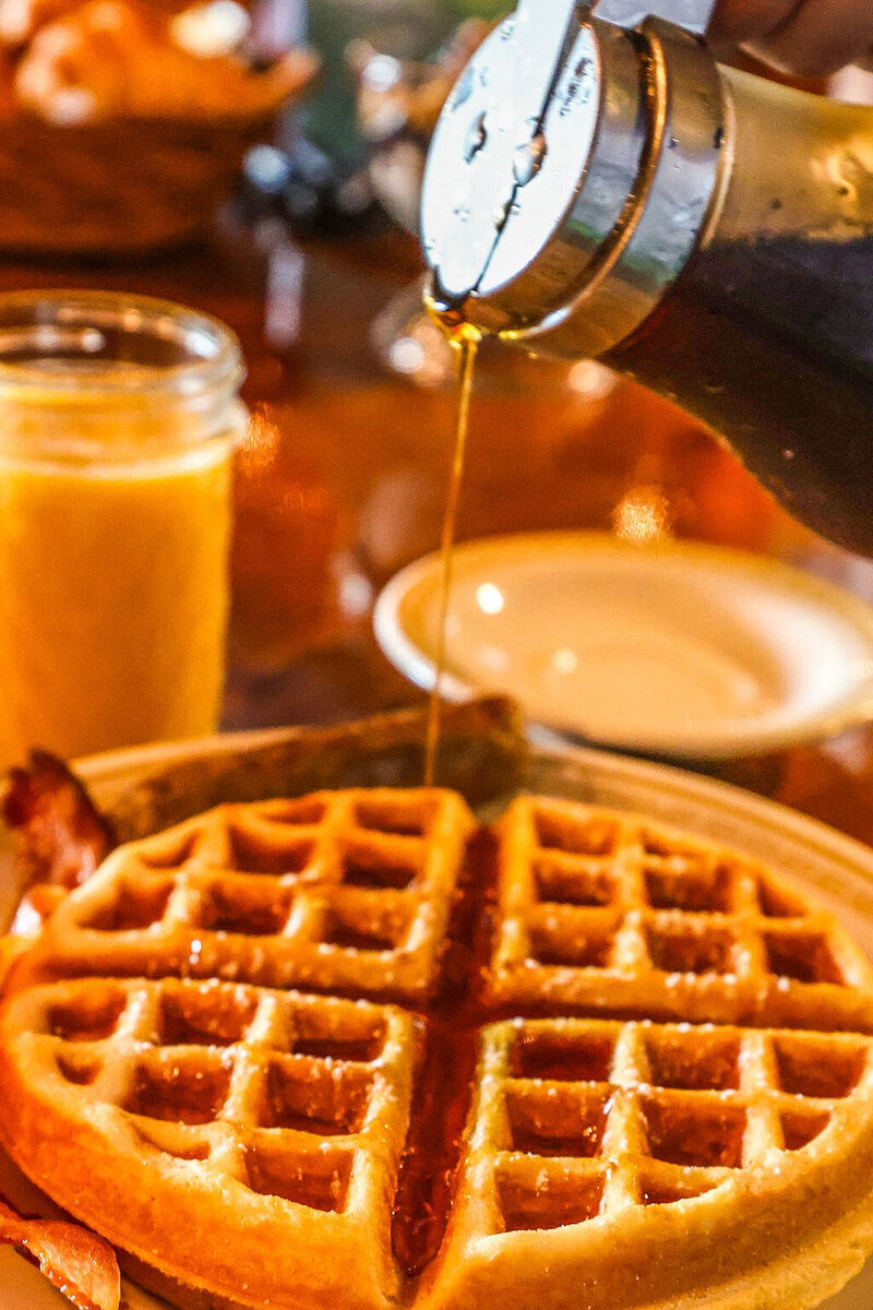 Hearty homemade breakfast at The Kitzhof Inn featuring waffles, sausage, and fresh Vermont maple syrup