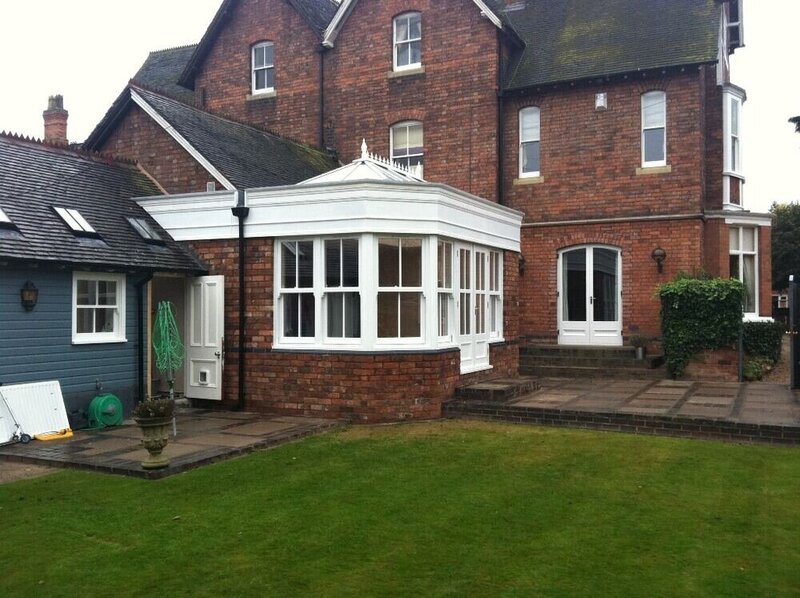 Large brick house with a white conservatory orangery extension.