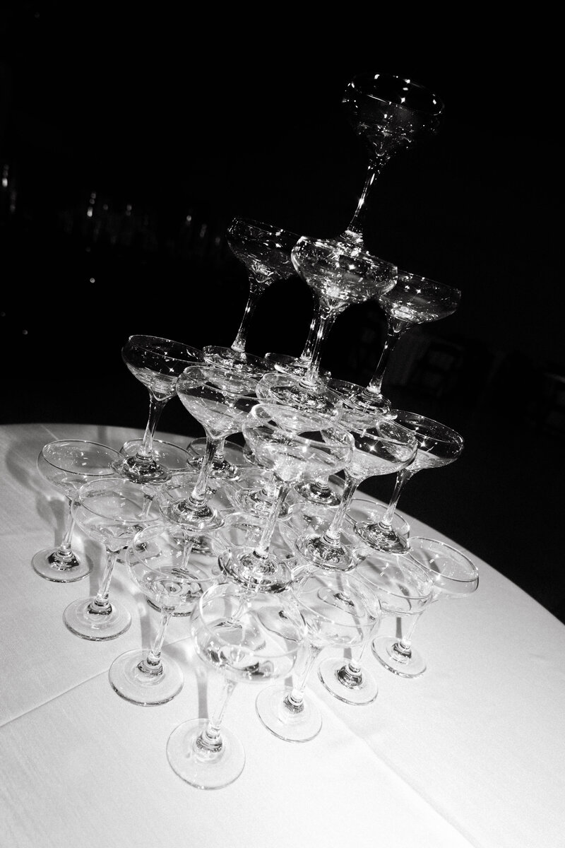 Black and white photograph of champagne tower stacked for wedding reception toast.