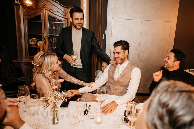 Sfeervolle videostill van een bruiloftsdiner met lachende gasten, professioneel vastgelegd door IMAI Wedding.