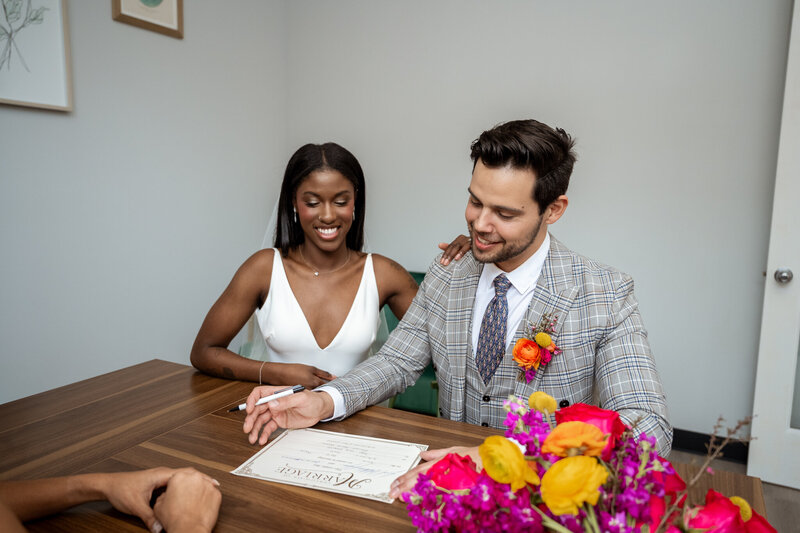 Sign and Celebrate Micro Venue, mixed race couple signing wedding documents.