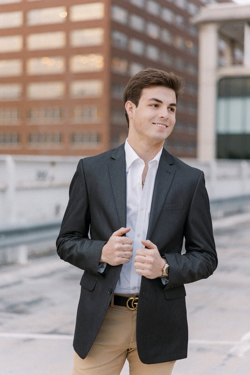dark haired senior holds sport coat on top of a parking garage in a bartlesville senior photo by melanie foster