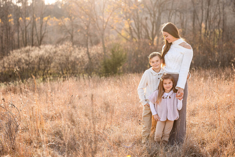 Cozy family of three poses in the setting sunlight in Southern Minnesota.