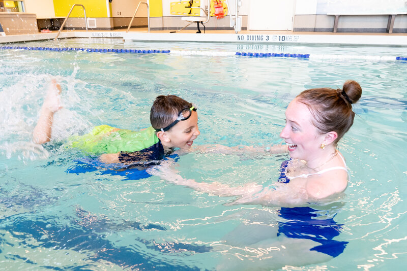 A woman compassionately teaches a child to swim, fostering a heartwarming bond and valuable life skills