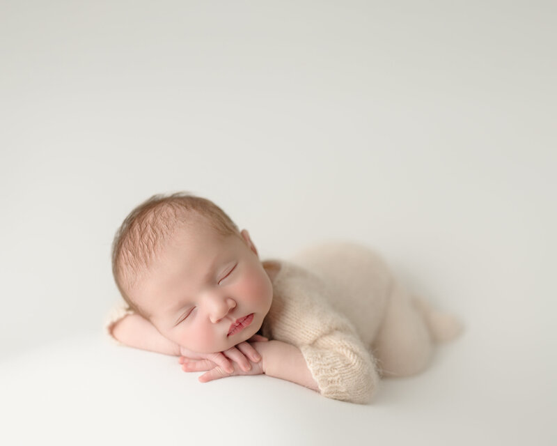Peaceful newborn portrait with baby girl posed with head on hands in soft cream tones – Paris, Ontario.