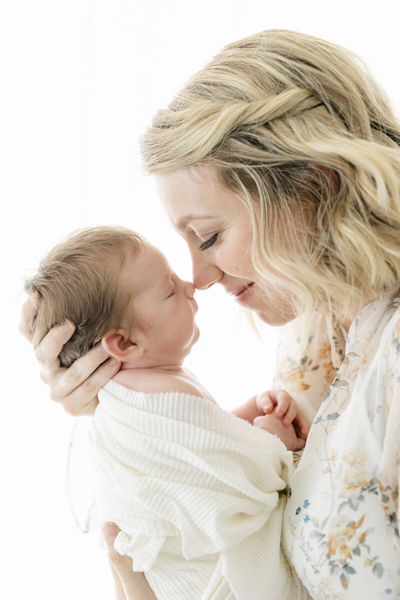 a mom touching noses with her newborn baby