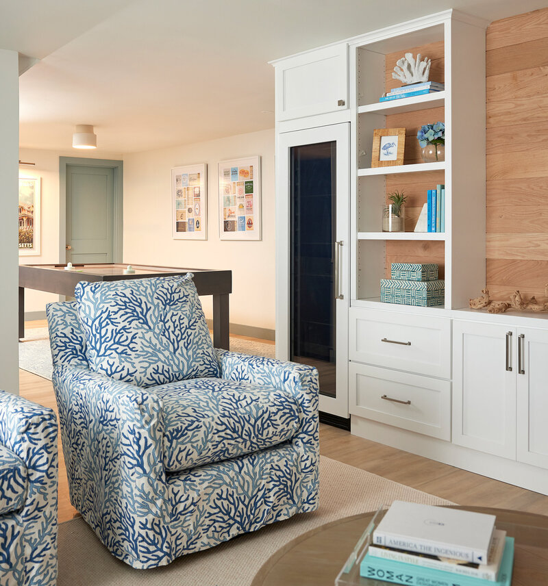 Comfortable living room featuring a blue patterned armchair, built-in white shelves with books and decor, and a modern coffee table