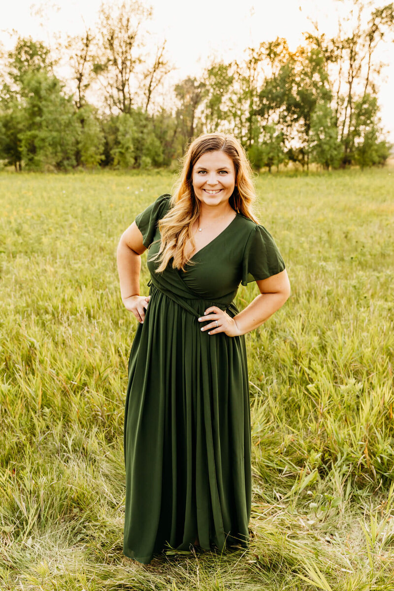 family photographer Ashley Kalbus standing in a field in striped sweater