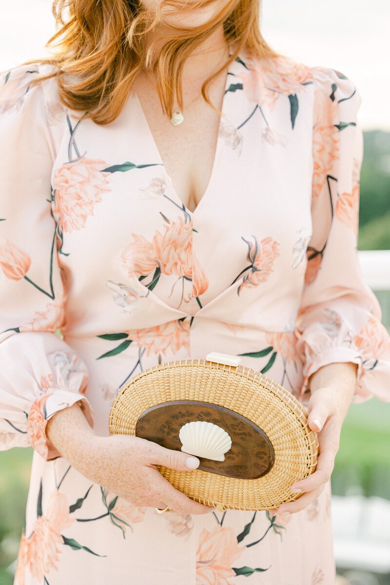 guest at a wedding in cape cod holding a custom rattan shell purse during cocktail hour