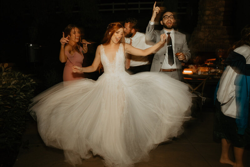 Bride and groom dancing at their reception with her dress flowing out around her and blurred from the motion.