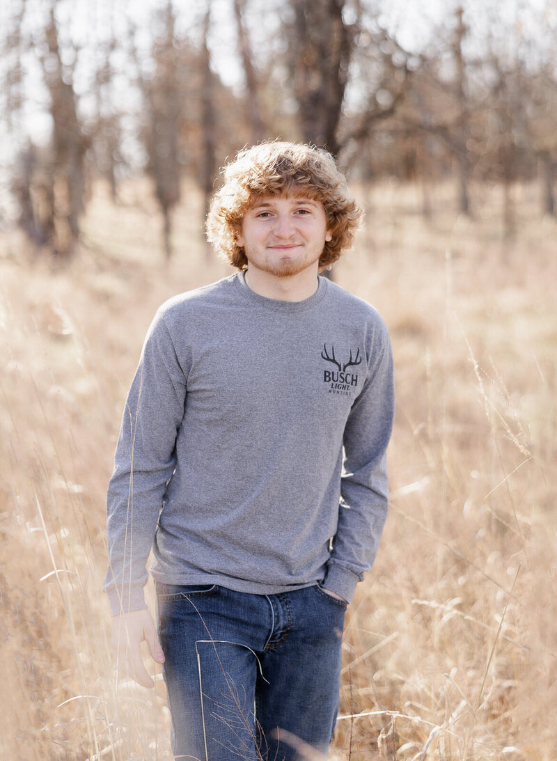 Senior guy standing in a field during a winter senior session in Farmington, Missouri. 