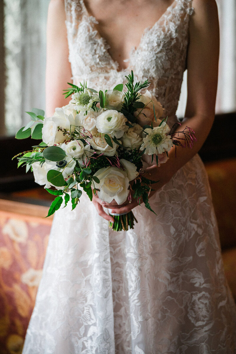Bride holding white rose and greenery bouquet