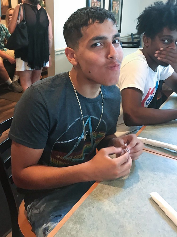 High school senior boy enjoying a cupcake while his friend looks on during senior model group dinner at Parkwood Inn in Greensburg, PA