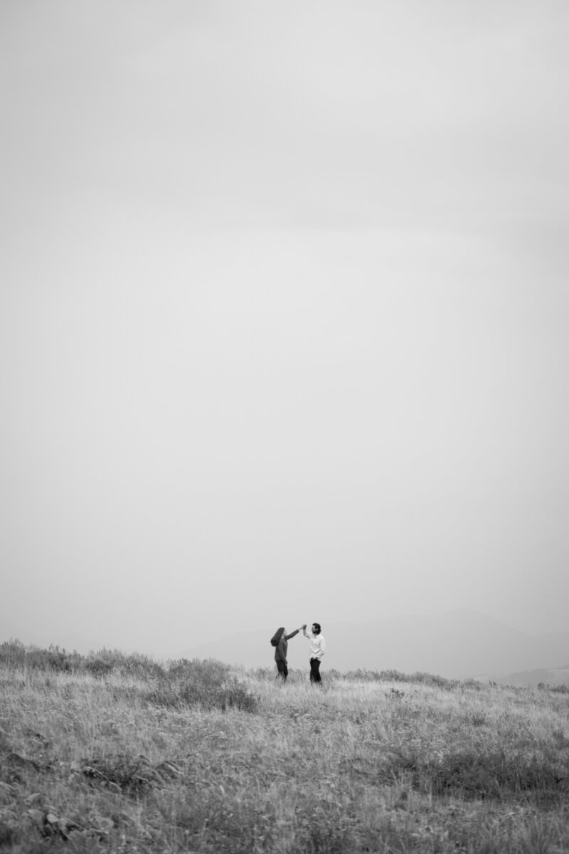 A couple dancing on a mountain during their engagement shoot.