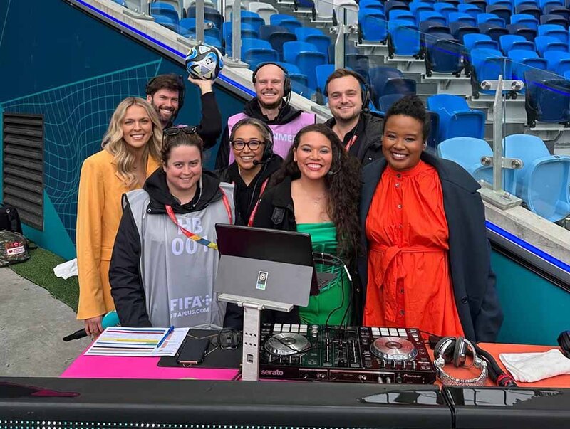 FIFA Women’s World Cup event team and DJ crew smiling together on sideline with DJ decks and equipment