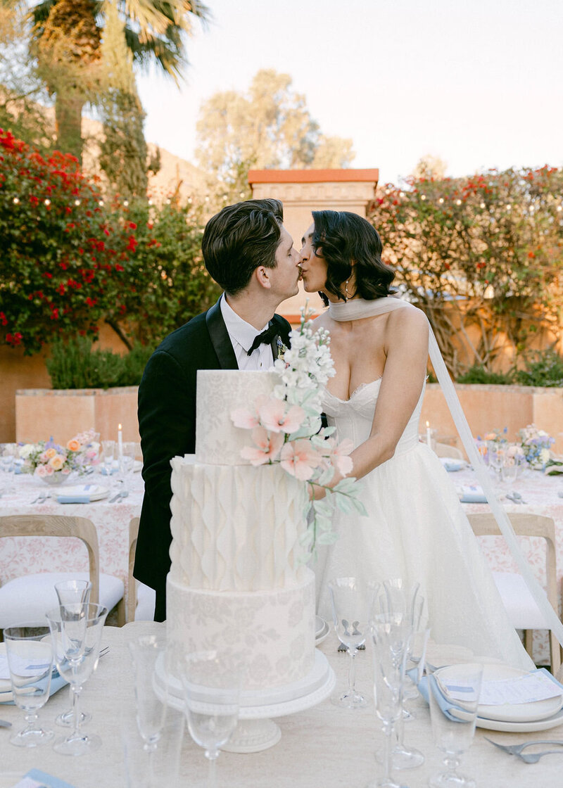 Bride and groom kissing at their cake table