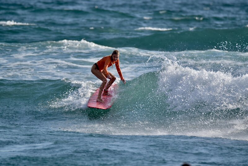 A surfer gliding over the waves as the sun sets over the Indian Ocean.